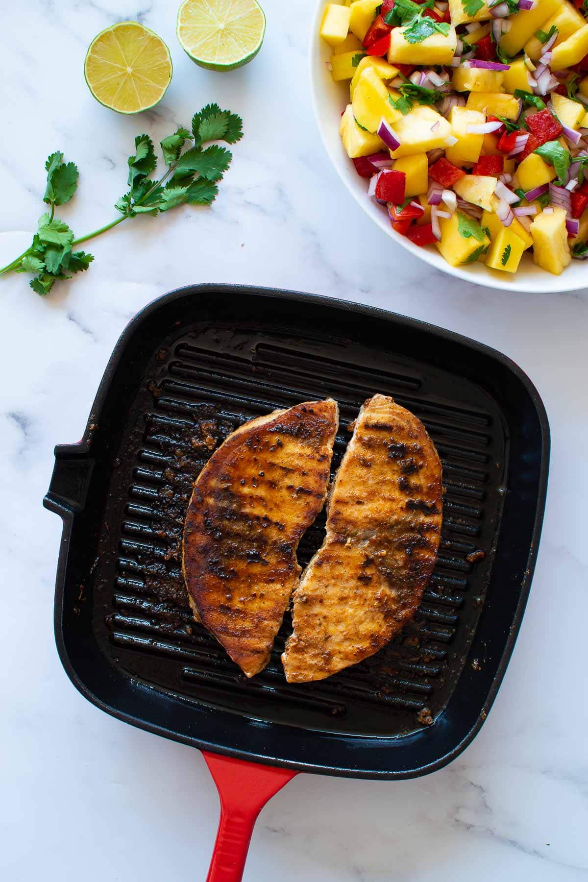 Pan seared swordfish with pineapple and mango salad in the background.