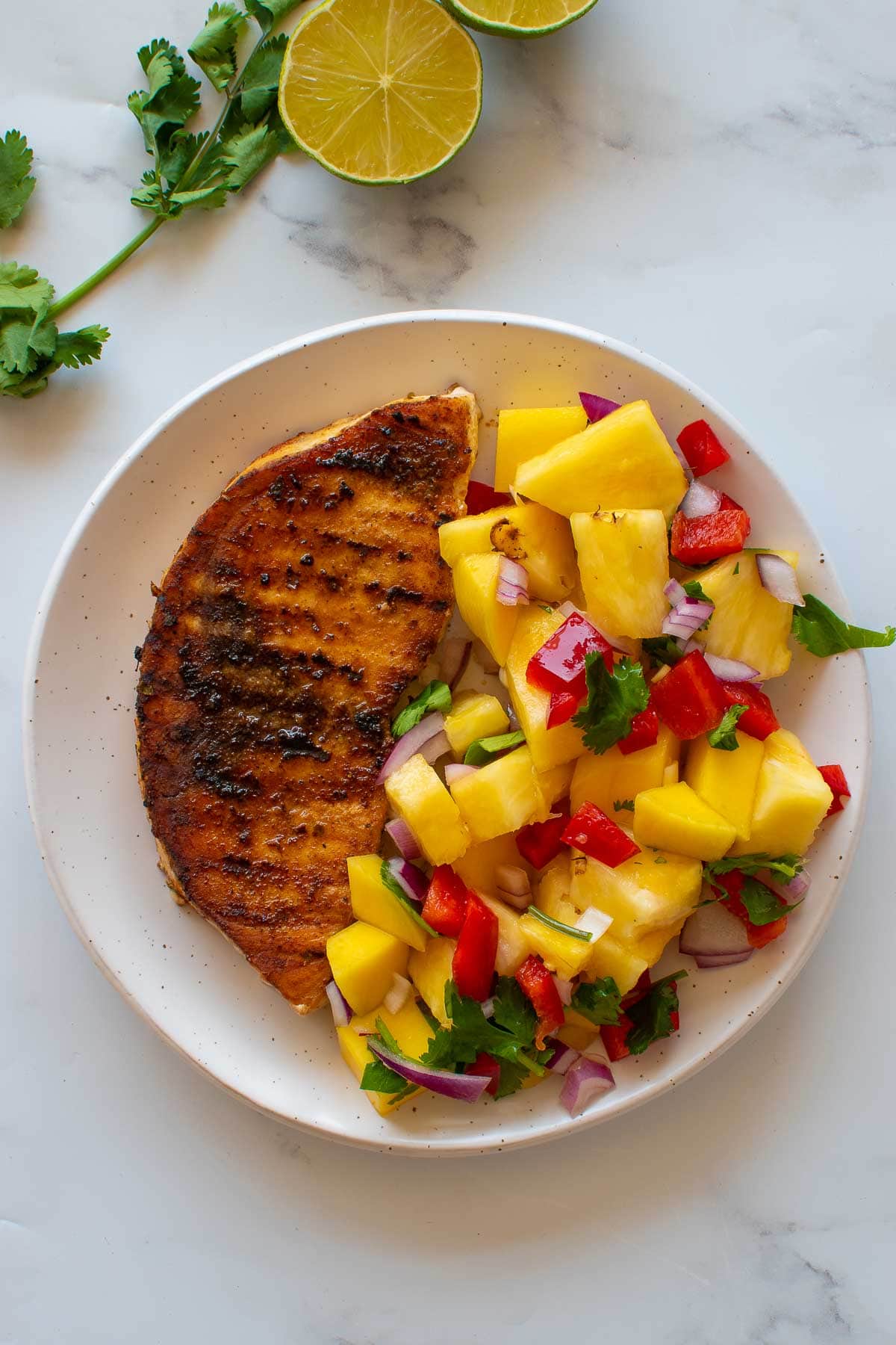 Blackened swordfish and pineapple salad on a plate.