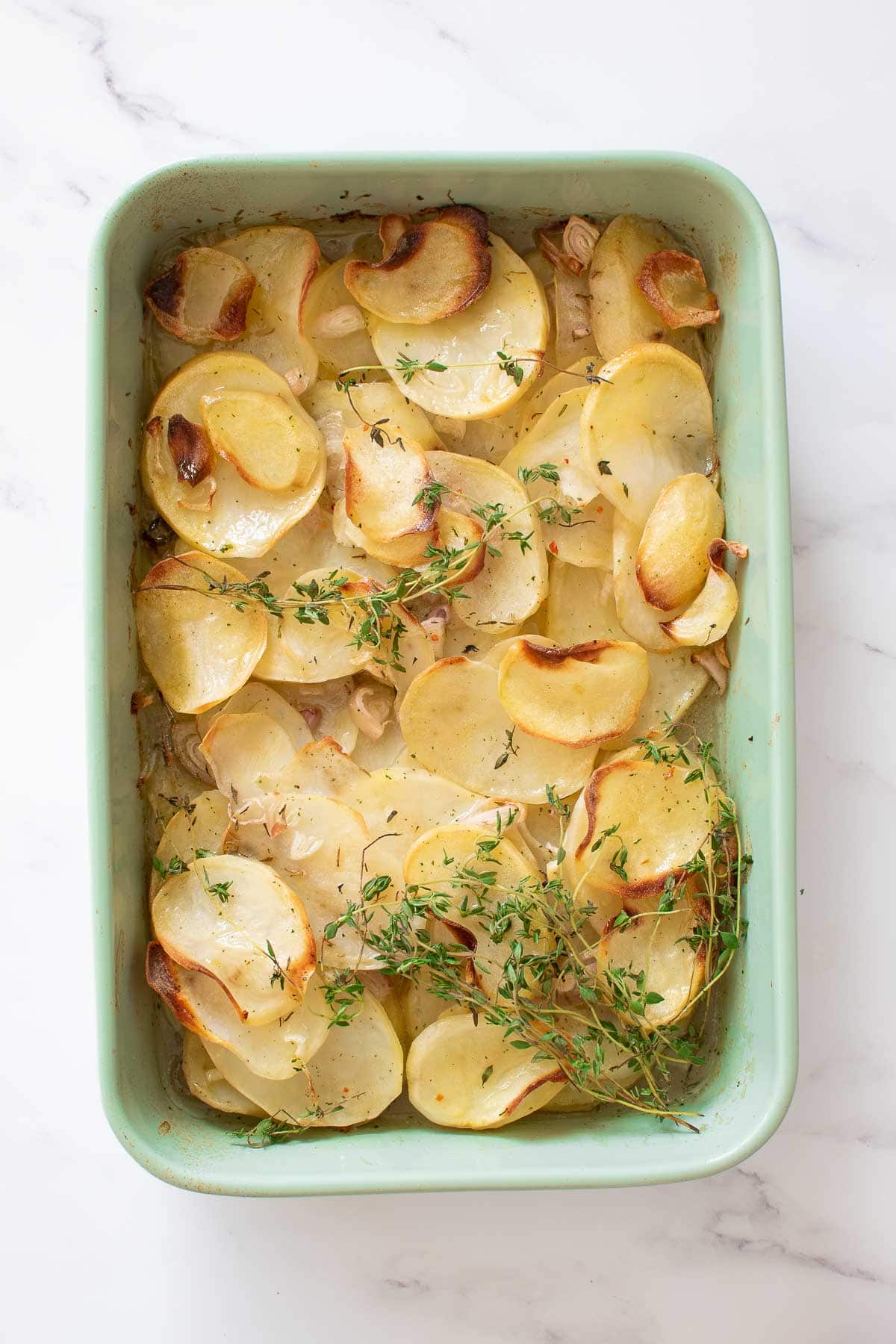 A dish of boulangere potatoes with thyme.