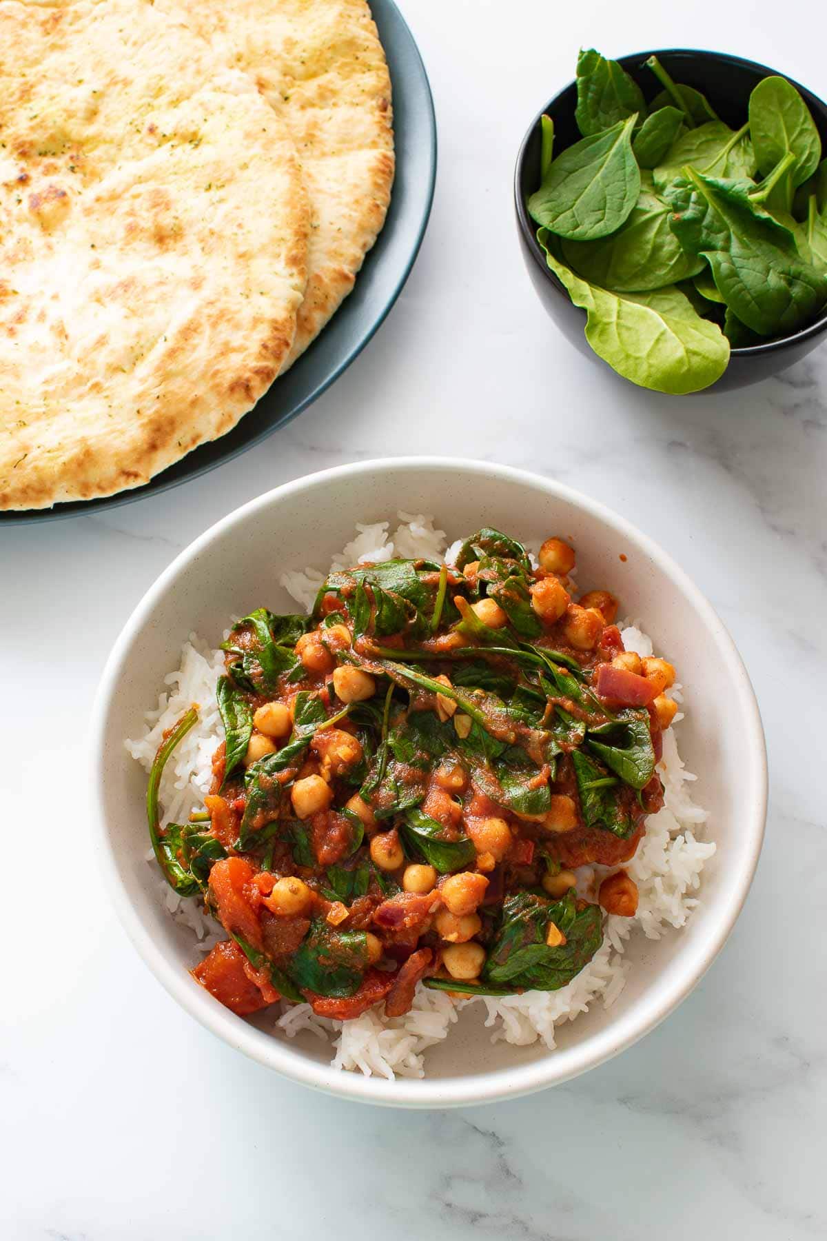 A bowl of curry with spinach and chickpeas.