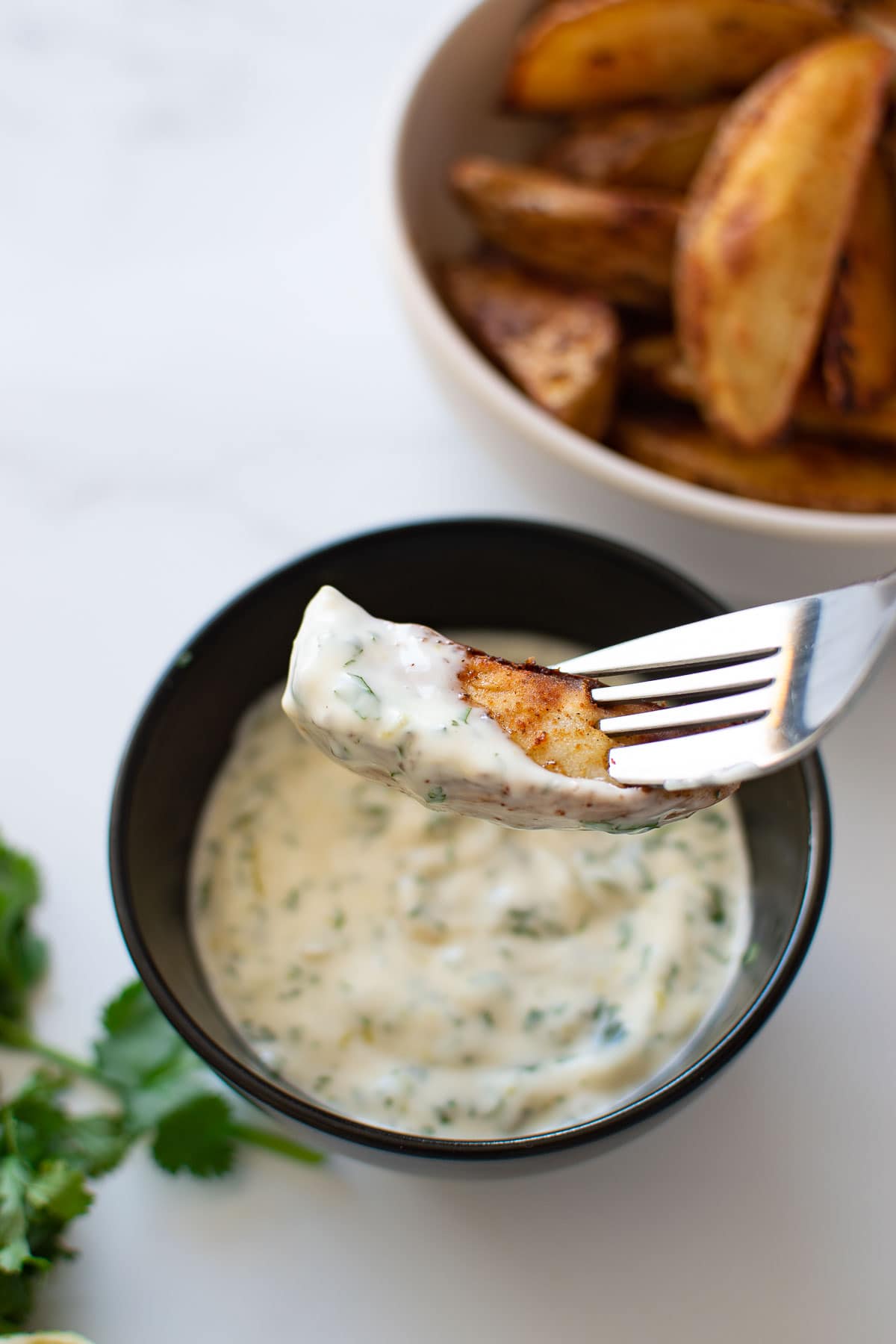 A potato wedge dipped in cilantro lime aioli.