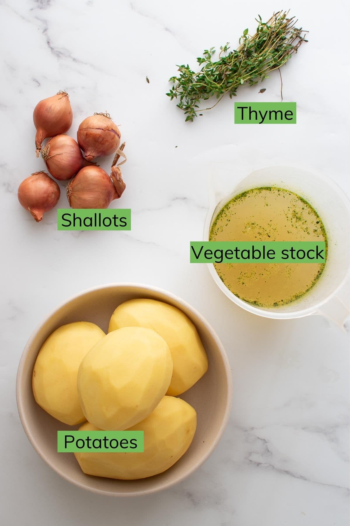 Thyme, shallots, vegetable stock and potatoes on a table.