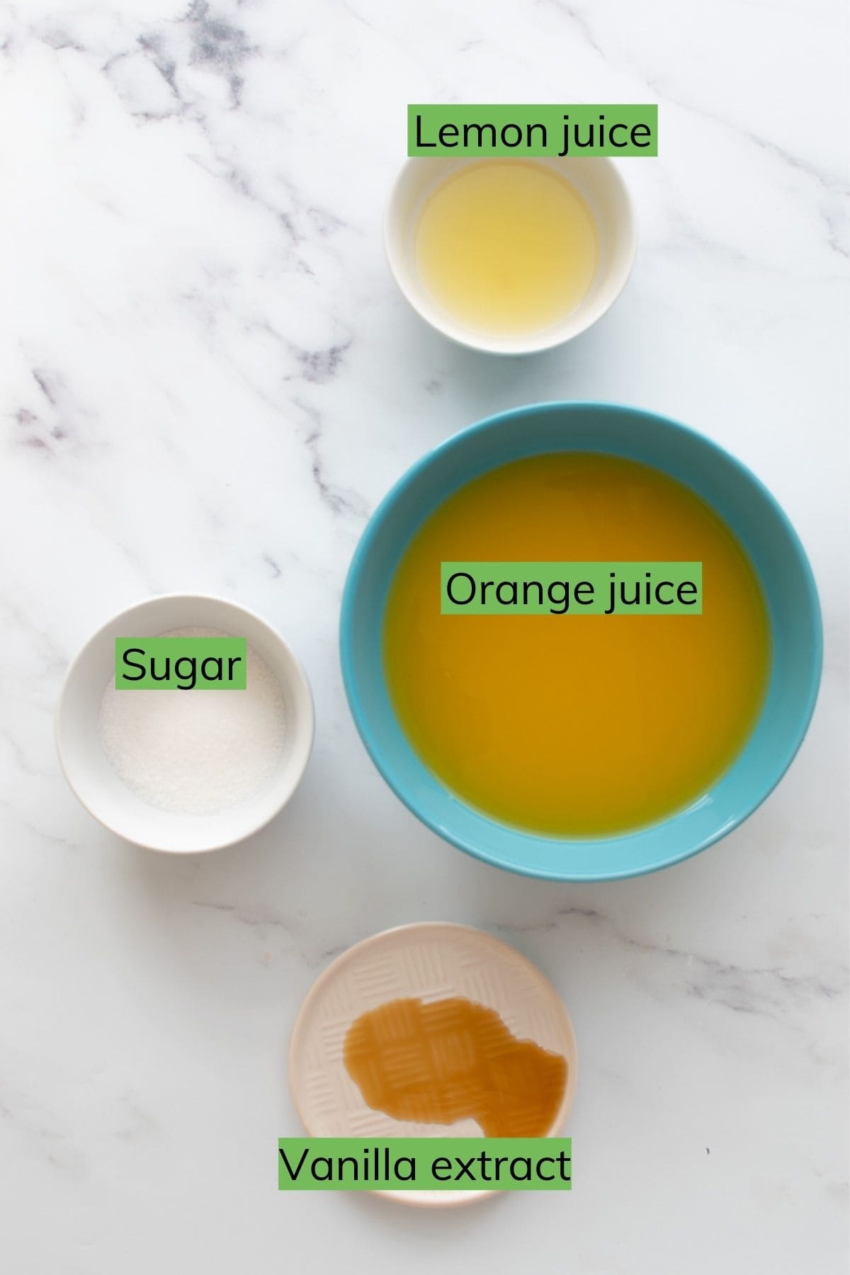 Orange juice, lemon juice, sugar and vanilla extract on a table.