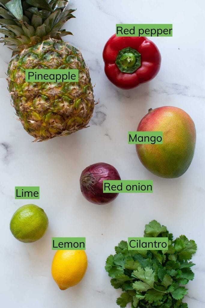 The ingredients required to make pineapple mango salsa laid out on a table.