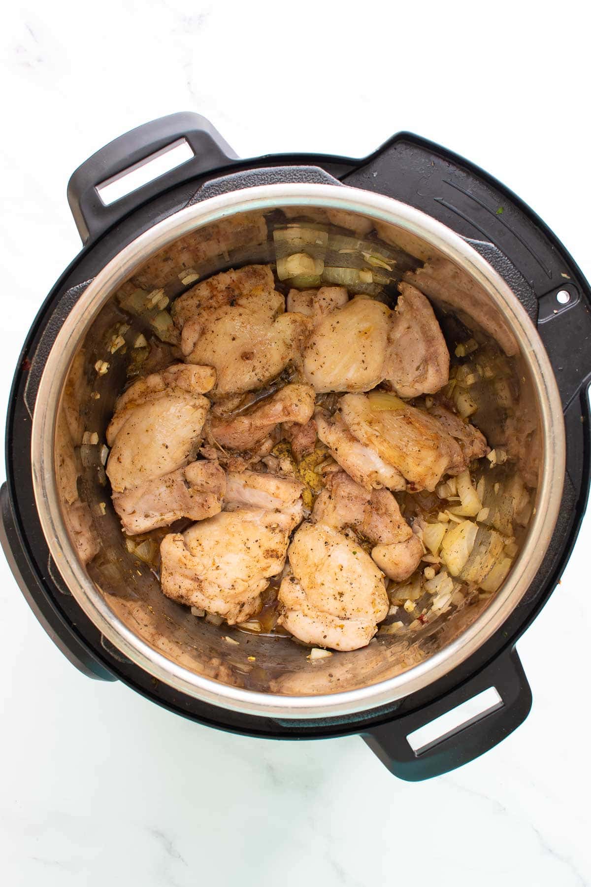Garlic, onion and chicken thighs in an Instant Pot.