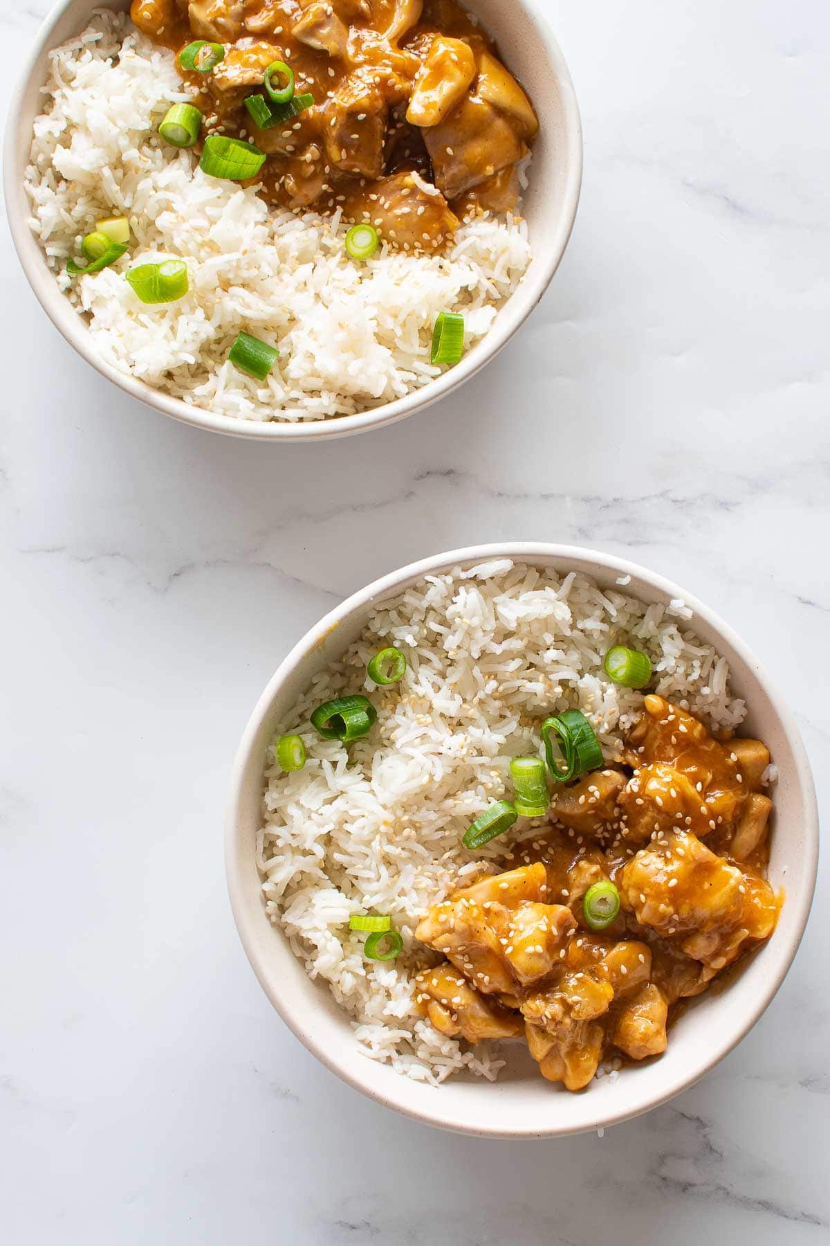 Two bowls with orange chicken and rice.