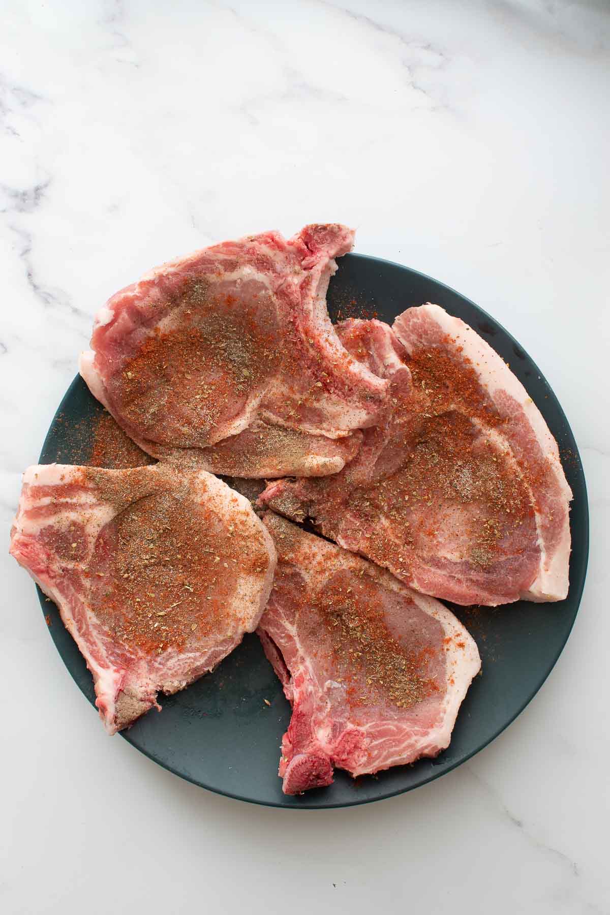 Seasoned pork chops on a plate.