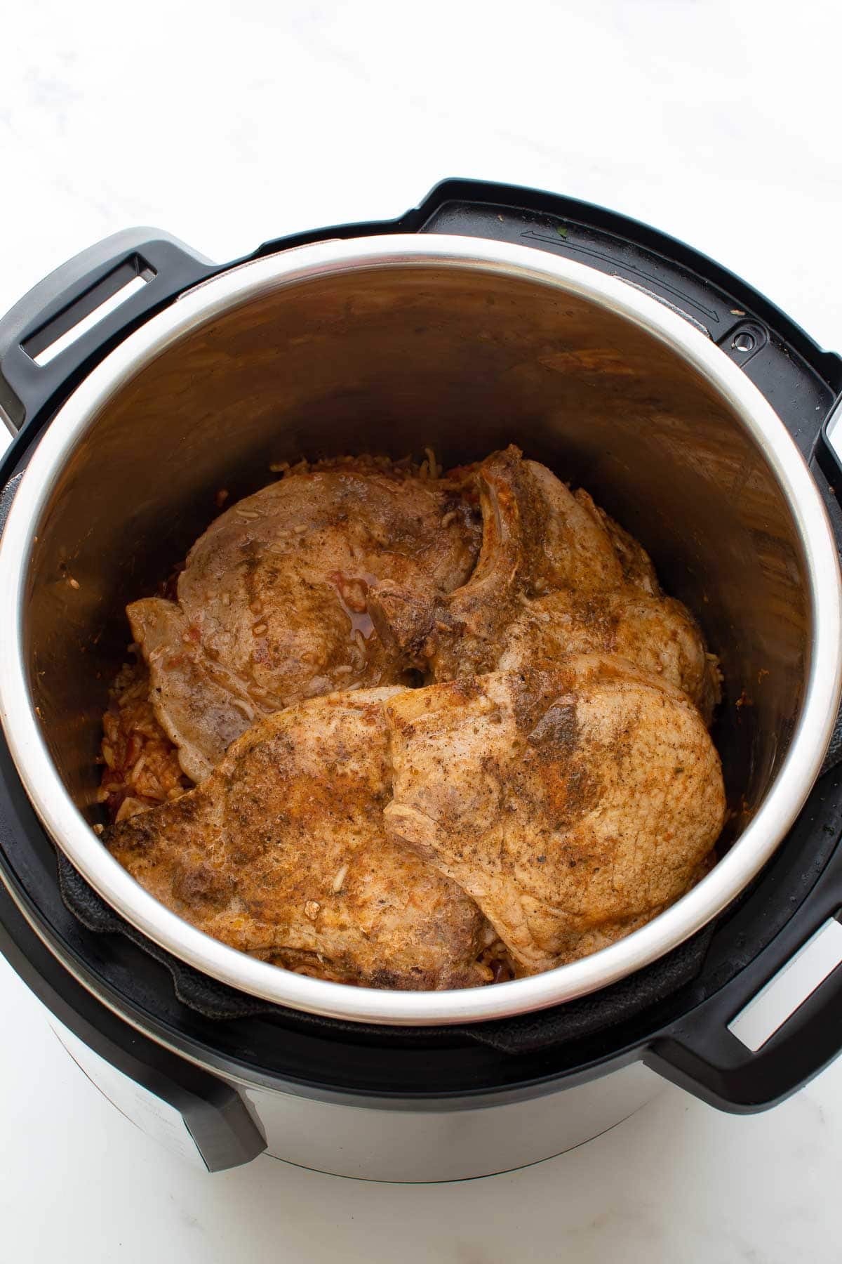 An instant pot with pork chops and rice.