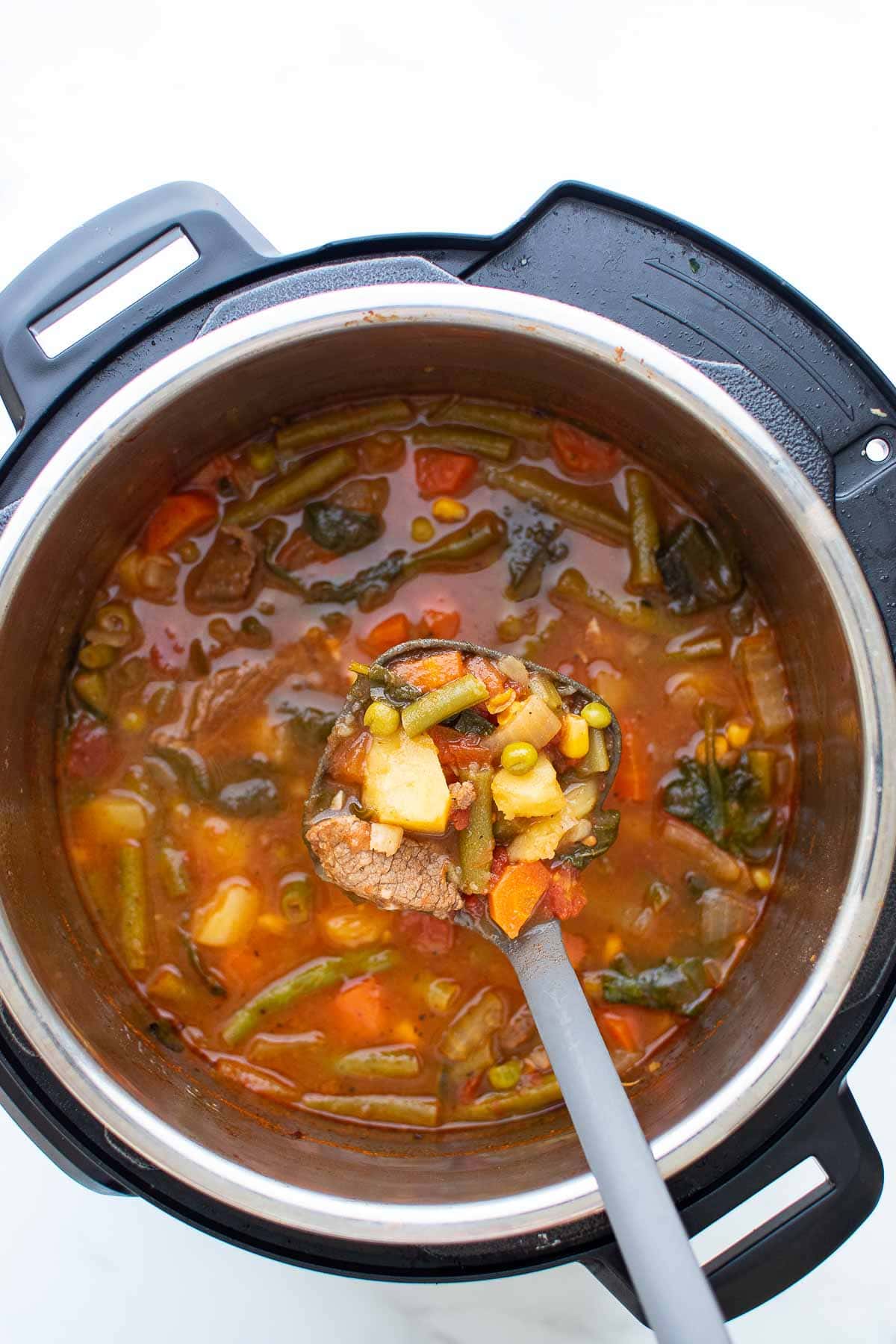 A ladle lifting a serving of soup from an Instant Pot.