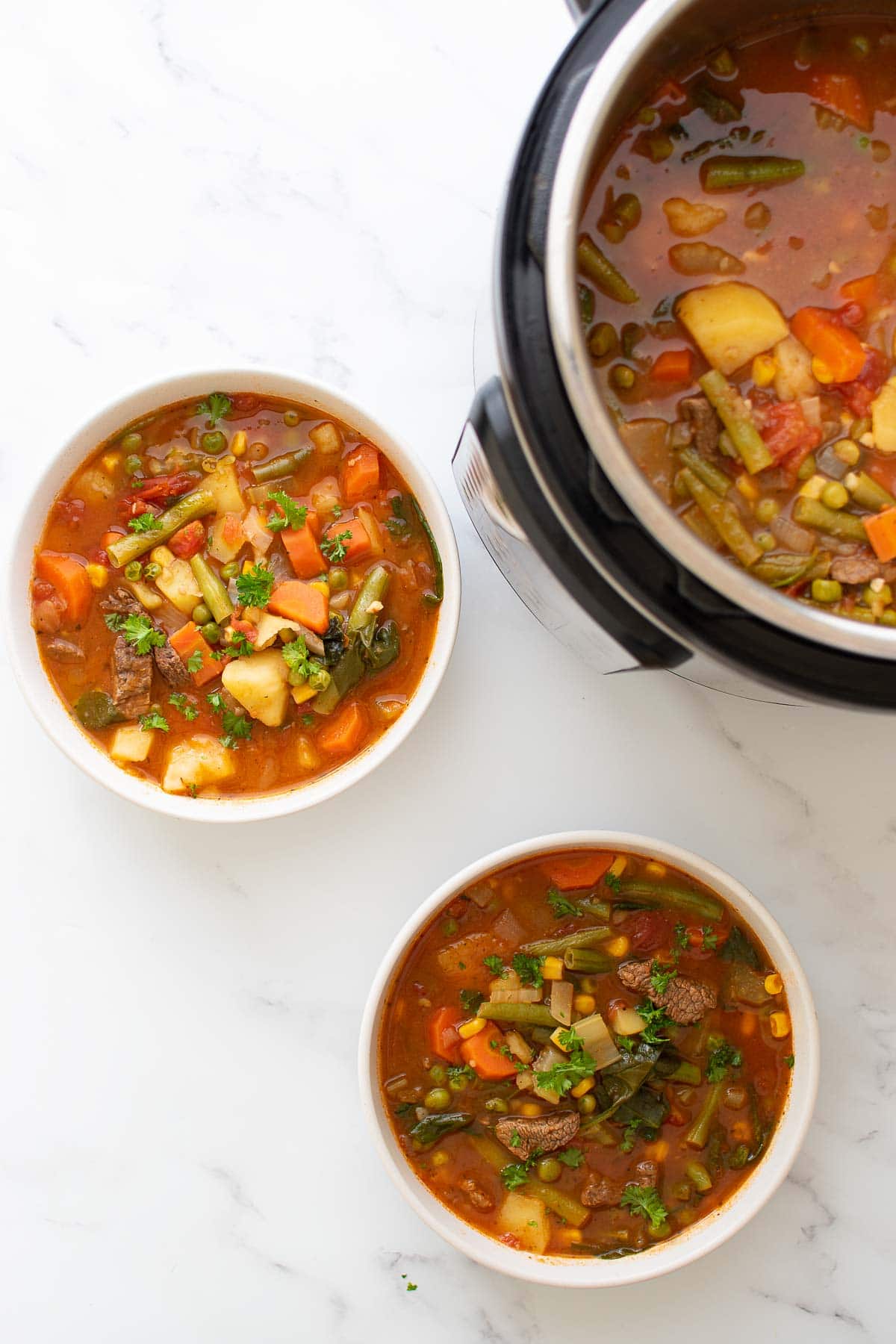 Two bowls of Instant Pot beef soup with vegetables.