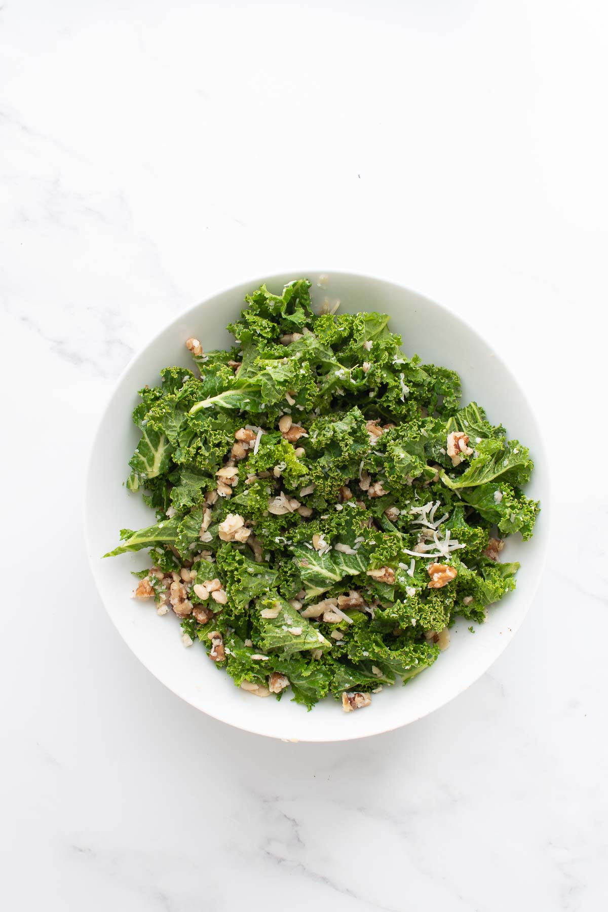 A bowl with lemon kale salad with nuts and parmesan.