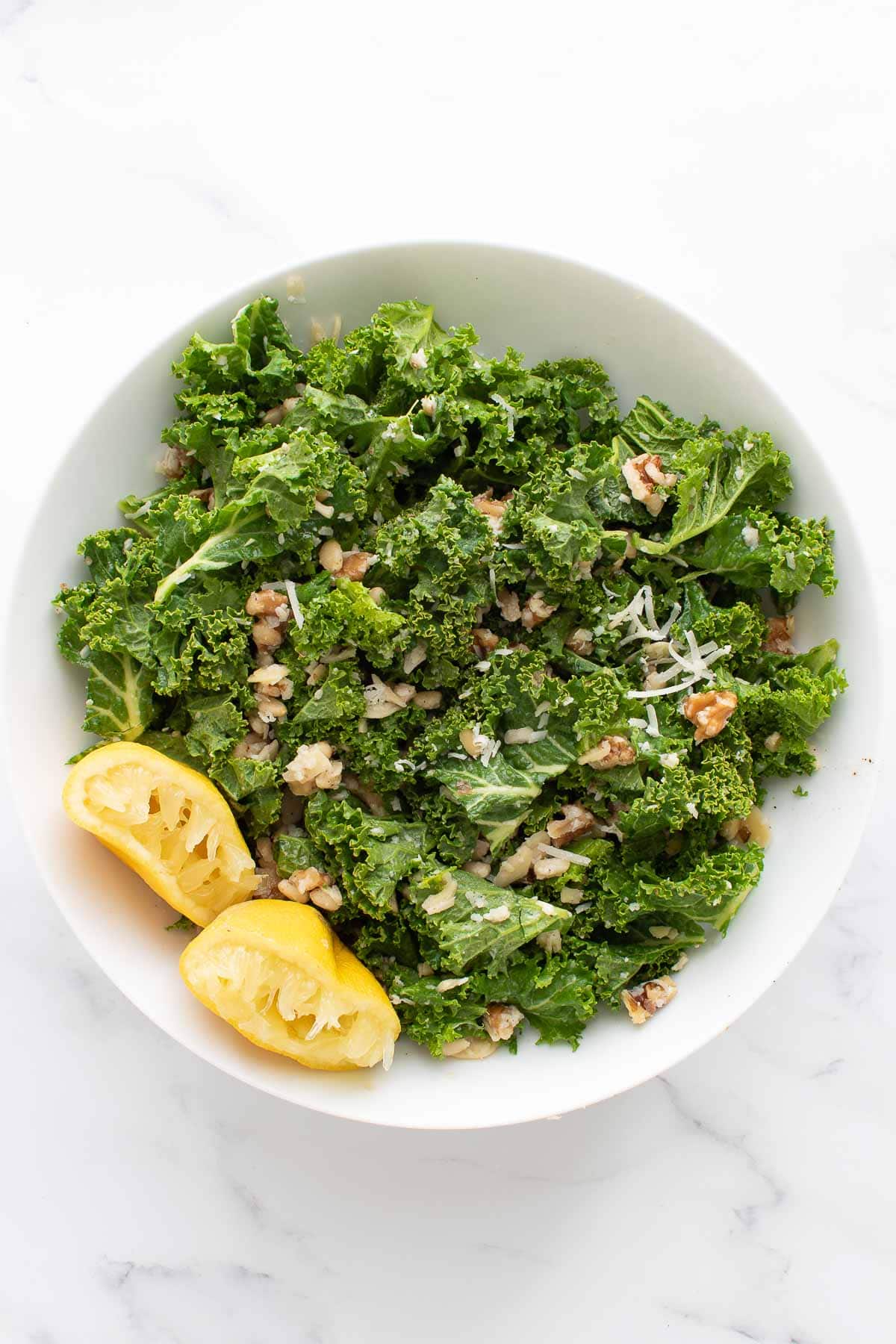 Lemon kale salad in a bowl, with lemon on the side.