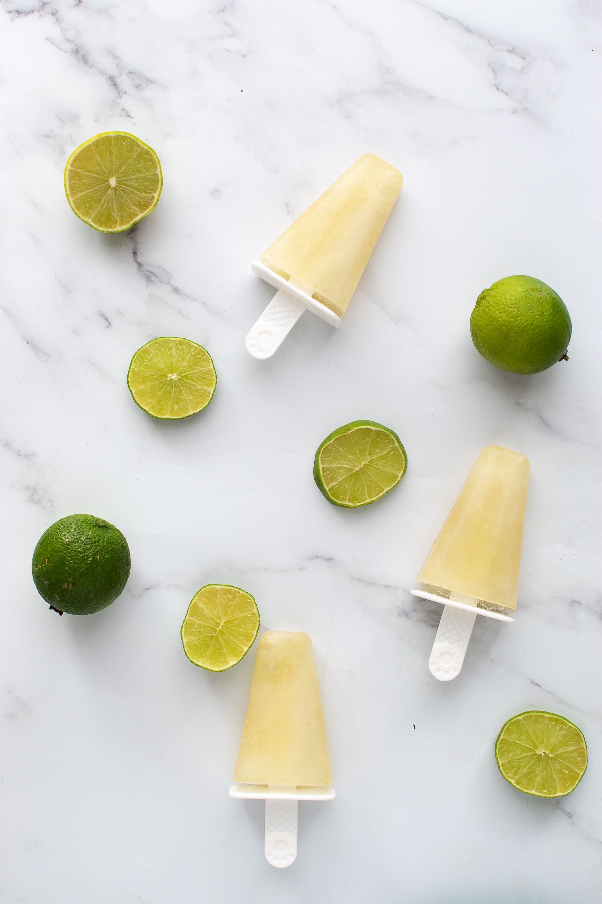 Lime popsicles and lime slices on a table.