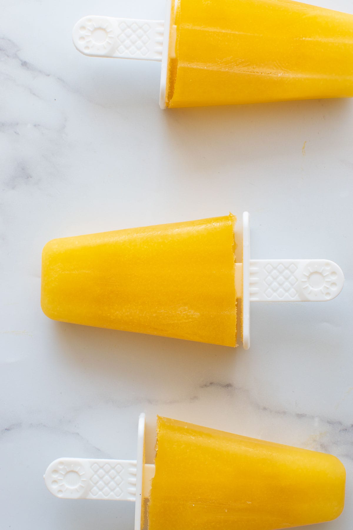 Close up of three mango ice pops.