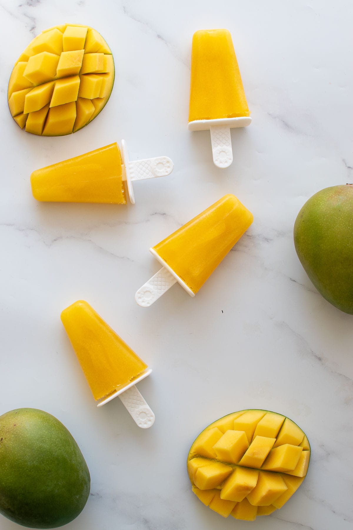 Mango popsicles and fresh mango on a table.