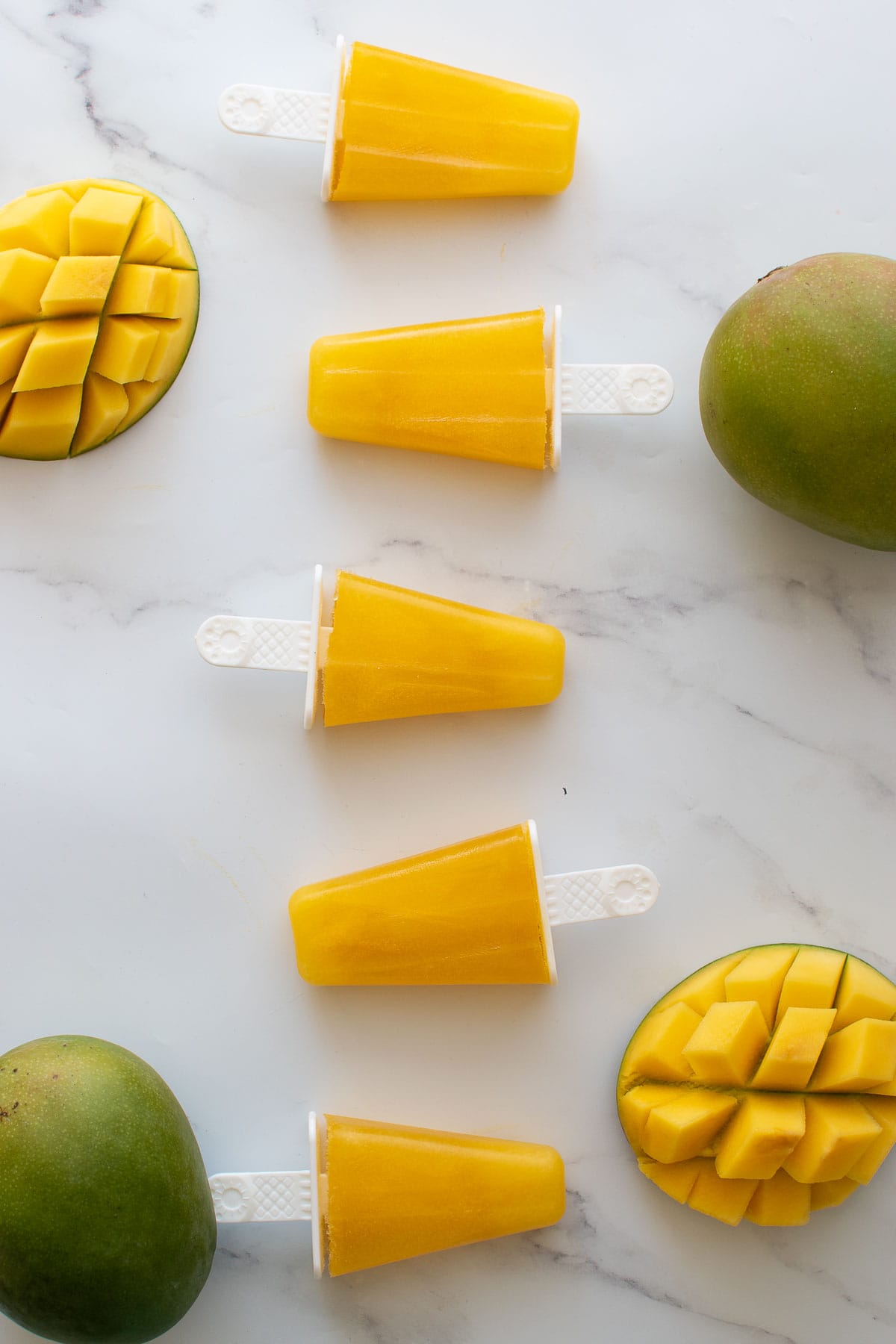 Mango popsicles lined up on a table.