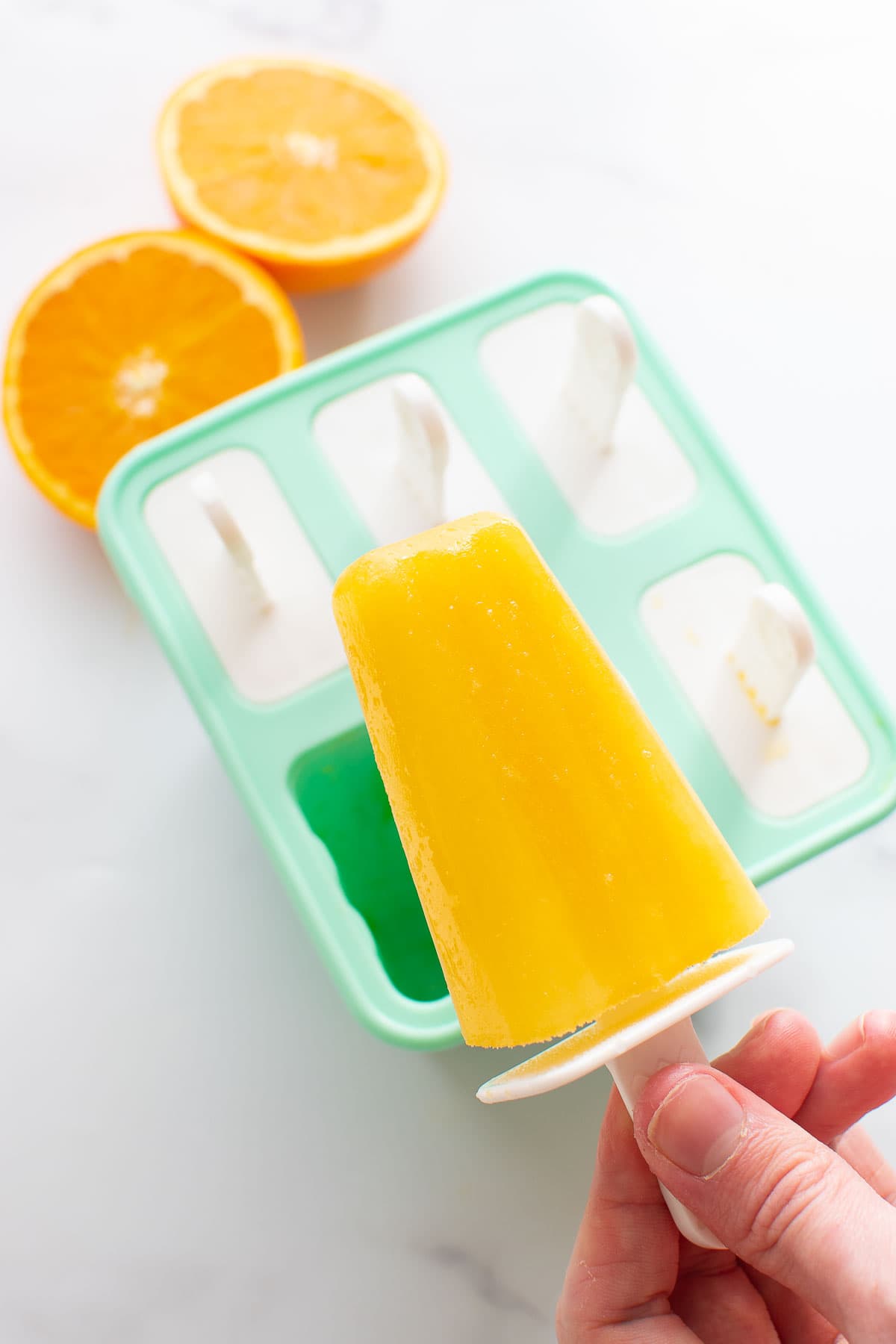 Holding an orange popsicle.