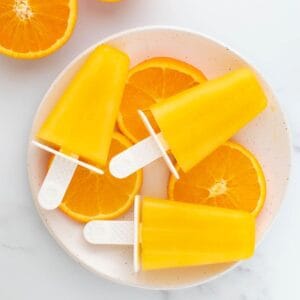 Orange popsicles laid on top of orange slices.