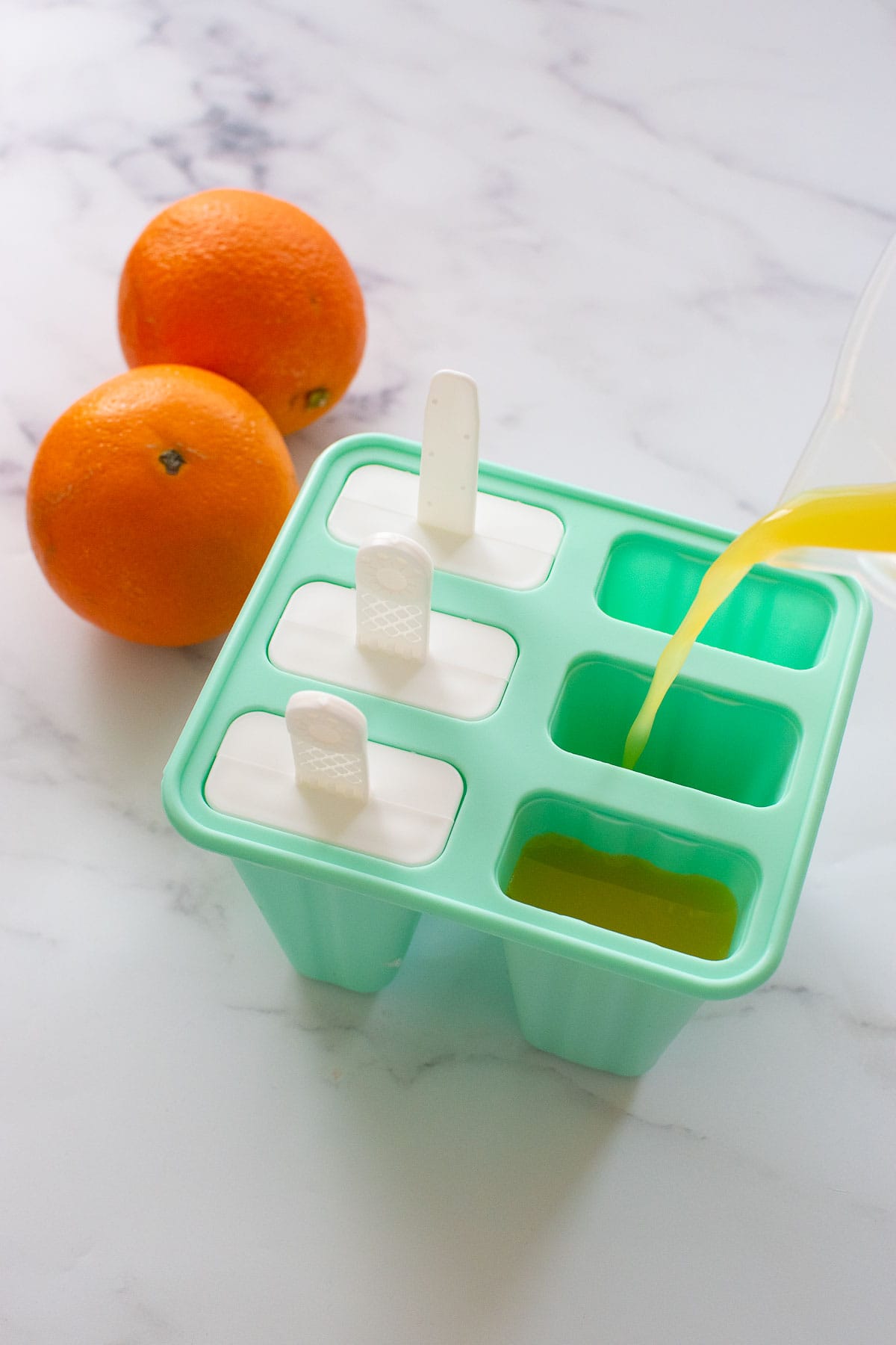 Pouring orange juice into a popsicle mould.