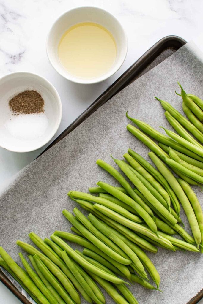 Seasoning, olive oil and green beans on a table.