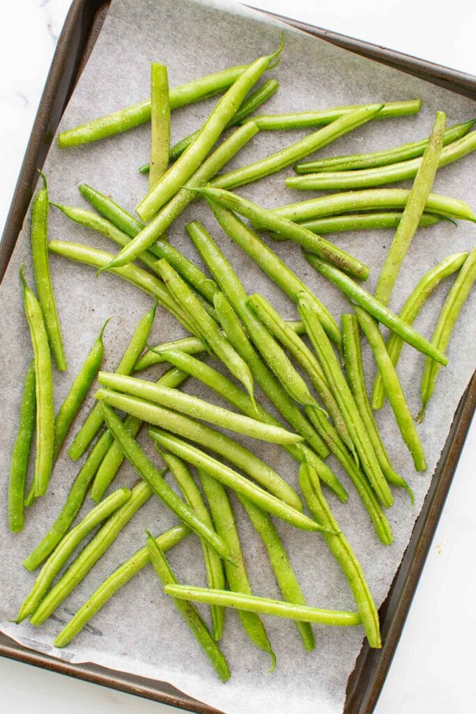 Seasoned green beans on a baking sheet.