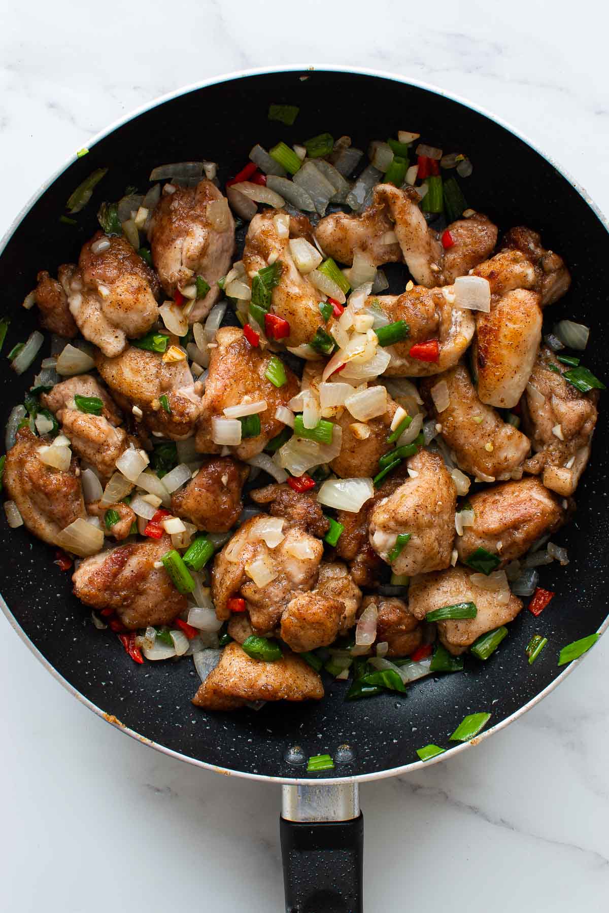 A skillet with salt and pepper chicken with chili.