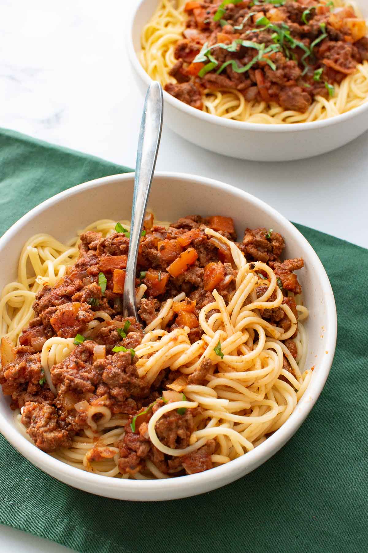 A bowl of spaghetti bolognese, with a fork.