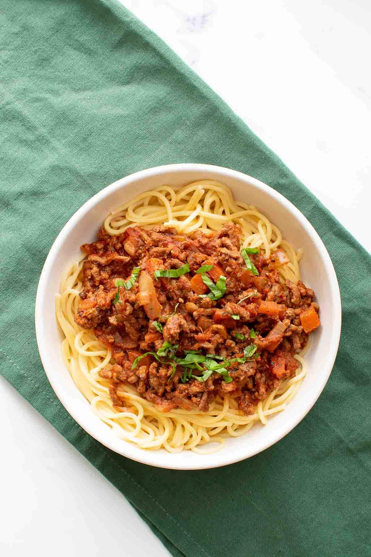 A bowl of pasta with bolognese sauce.