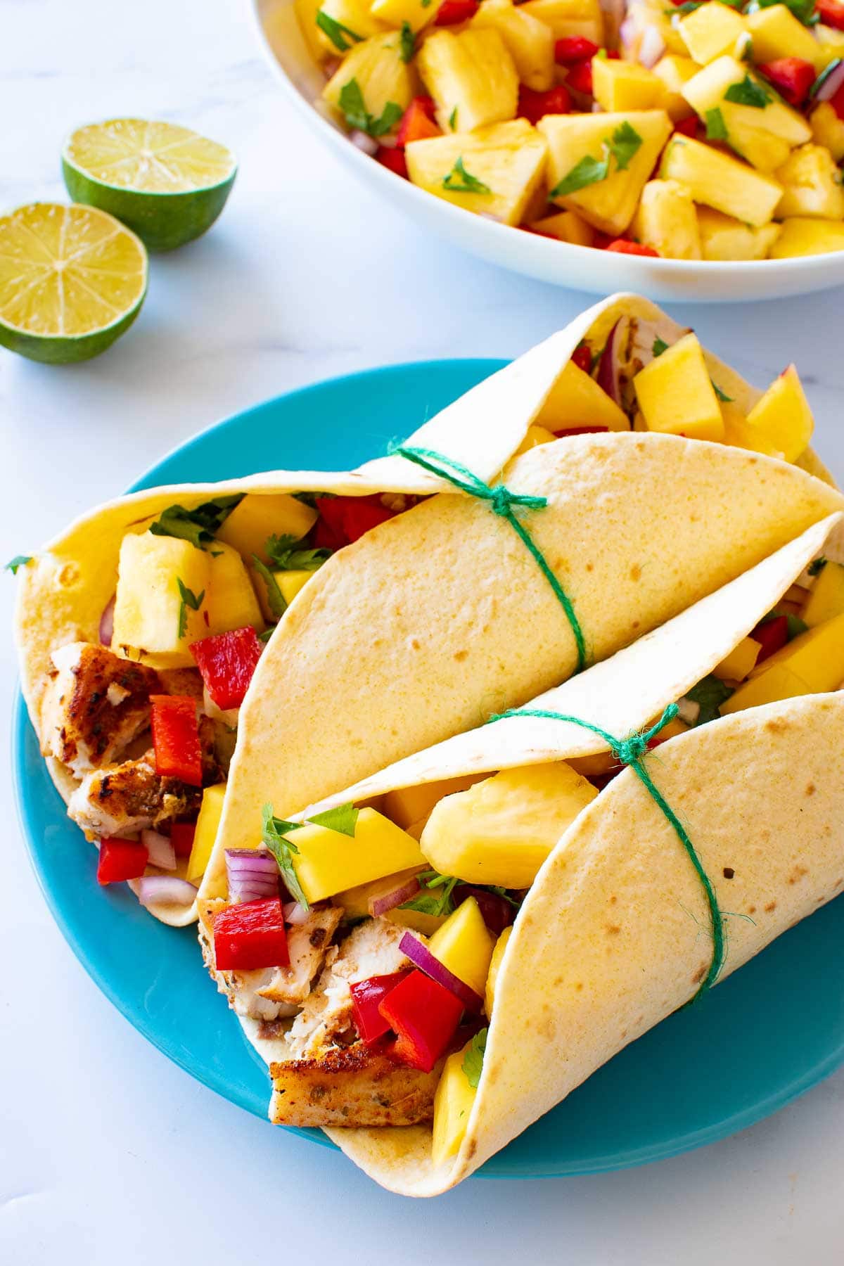 Swordfish tacos on a plate, with lime and salsa in the background.