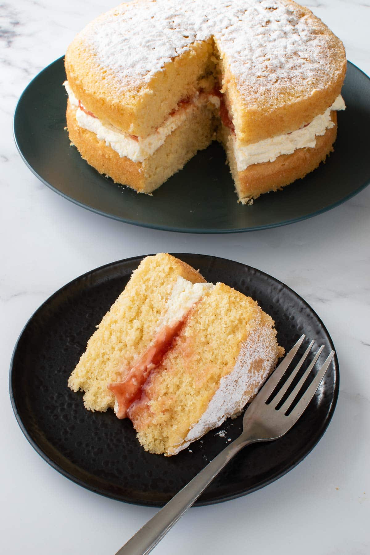 Victoria sponge cake with a slice cut out and plated on the side.