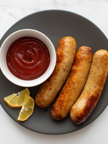 Air fried brats and ketchup on a plate.