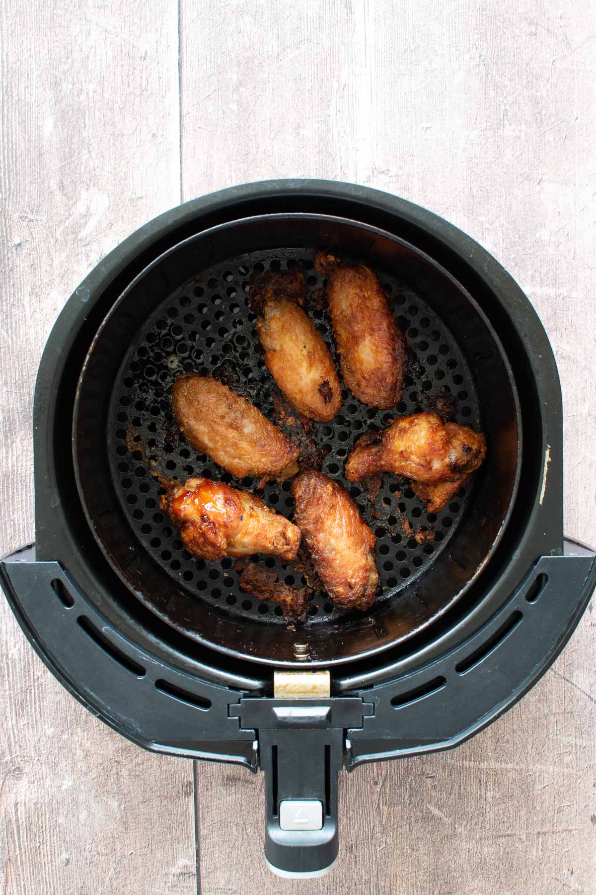 Cooked chicken wings in an air fryer.