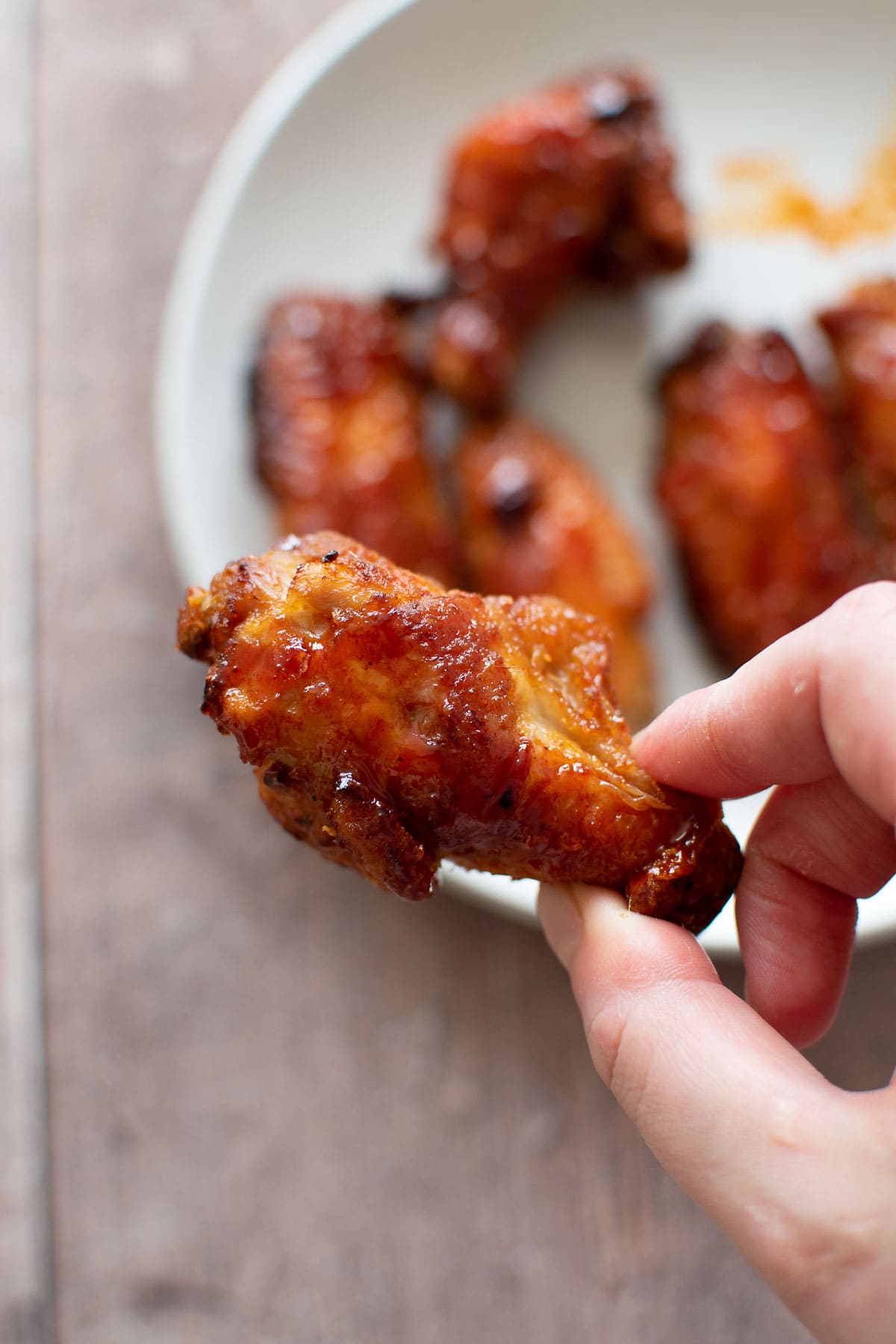 A hand holding an air fried chicken wing.