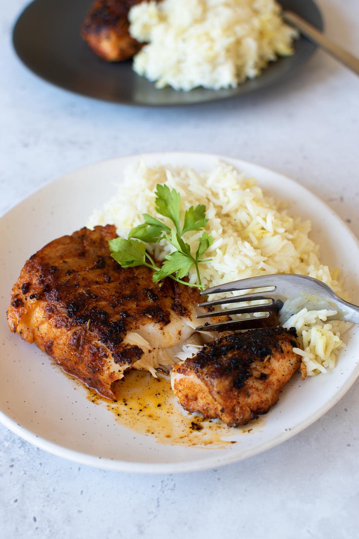 Blackened cod and rice, with a fork cutting into the fish fillet.