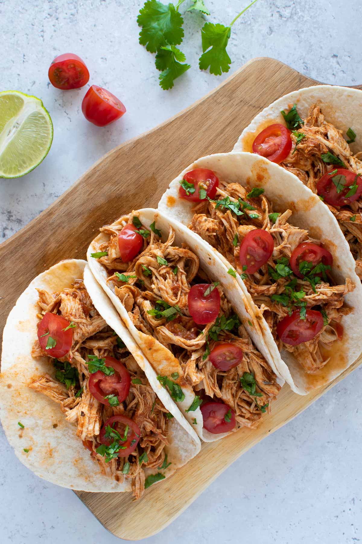 Instant Pot pulled chicken tacos on a cutting board.