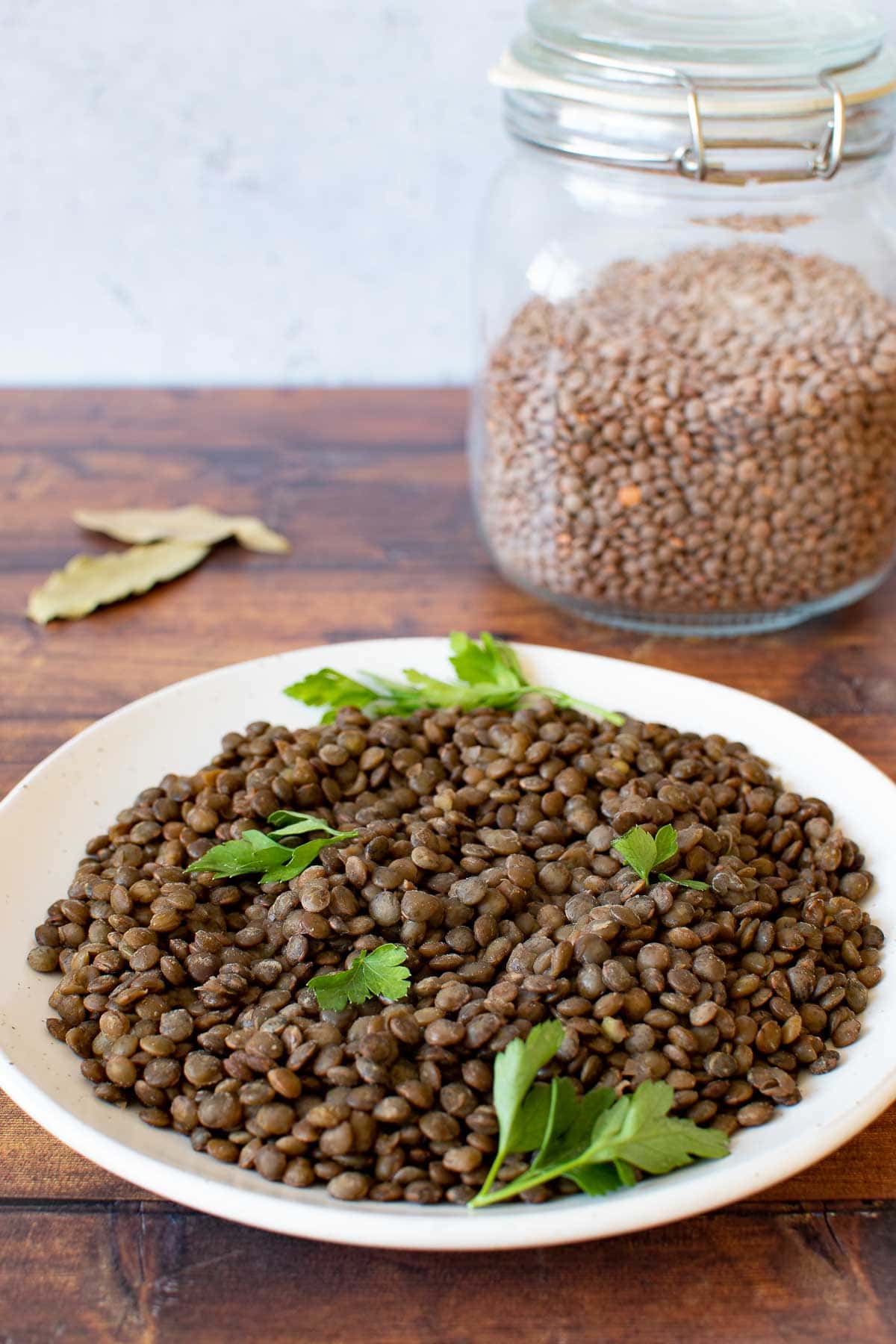 A plate with lentils, with a mason jar with dry lentils in the background.