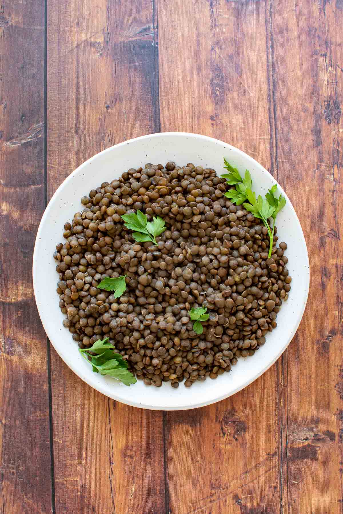 A plate of cooked lentils on a wooden table.