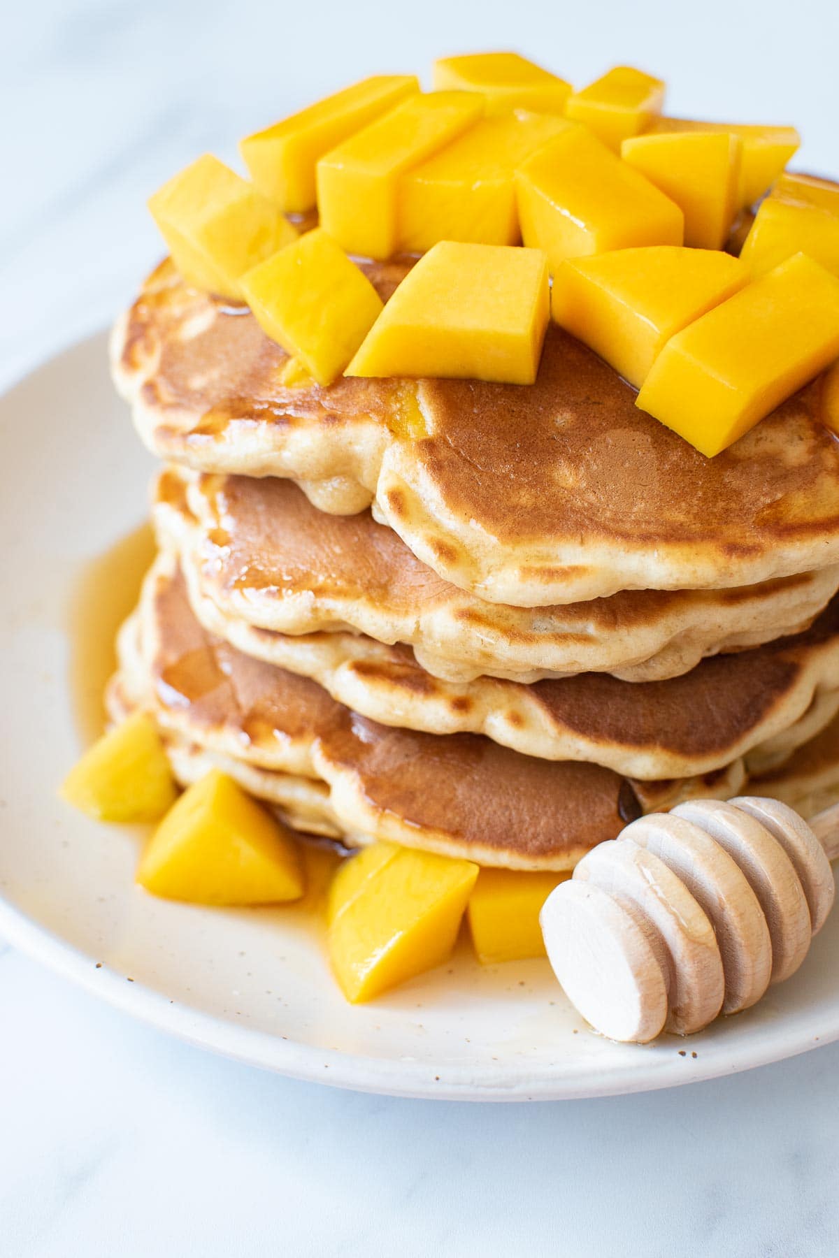 Close up of a stack of pancakes with mango.