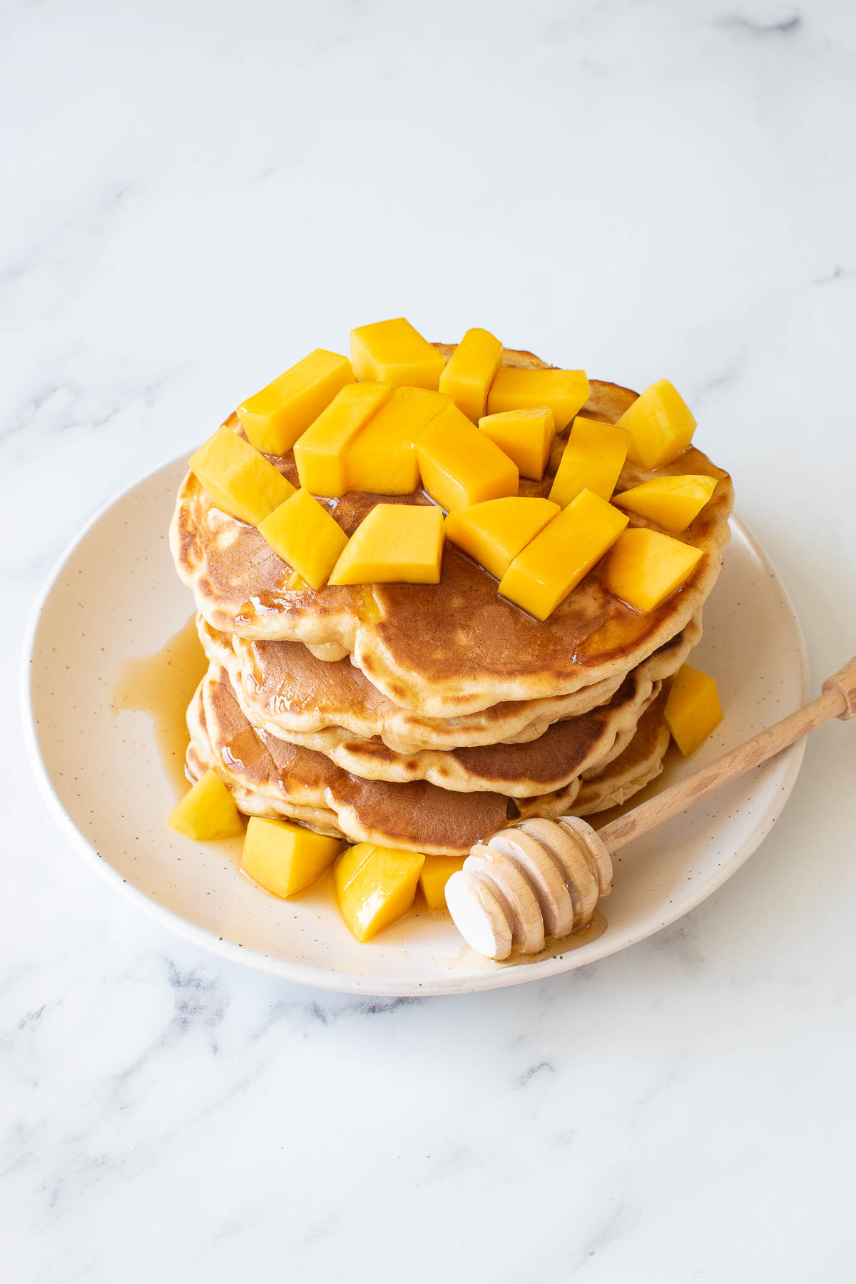 A stack of mango pancakes, with diced mango on top.