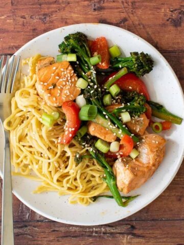 Salmon stir fry on a plate with noodles.