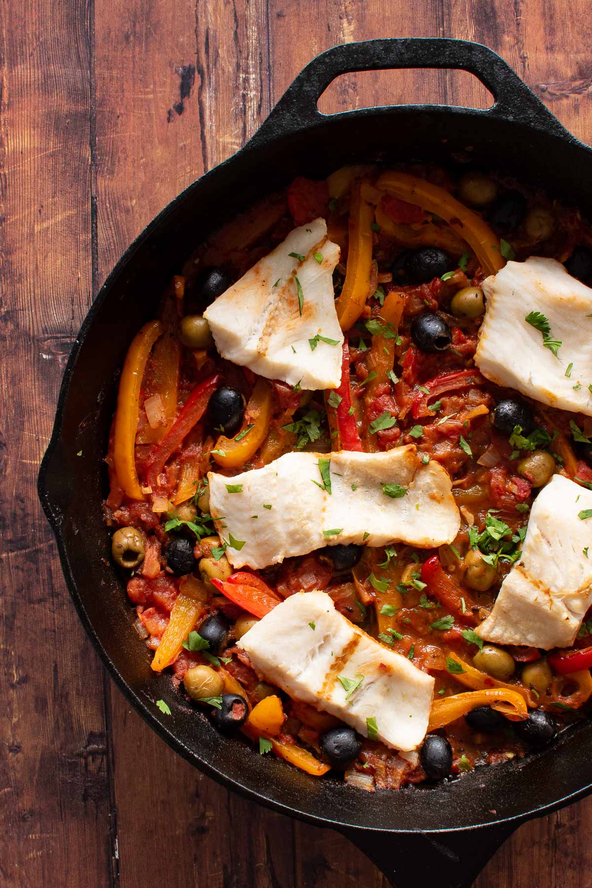 Baked hake and vegetables in a cast iron pan.