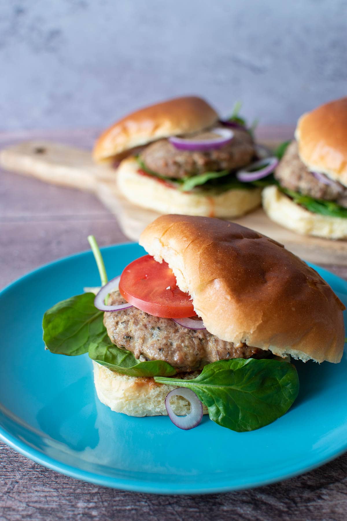 A turkey burger with spinach, tomatoes and onion.