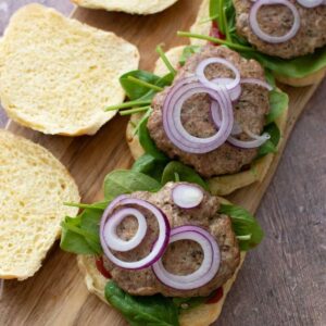 Three baked turkey burgers on a wooden board.