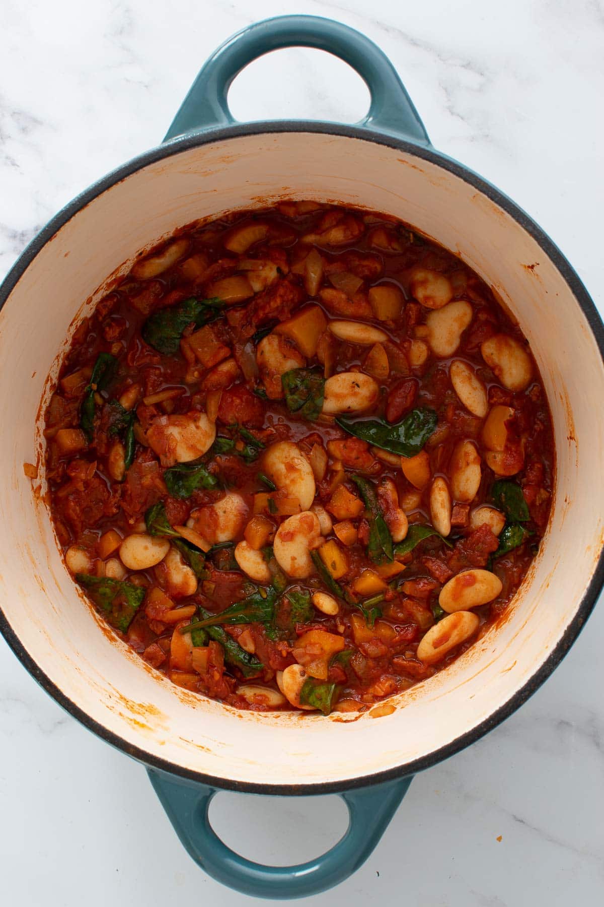 Butter bean stew with chorizo in a blue cast iron pot.