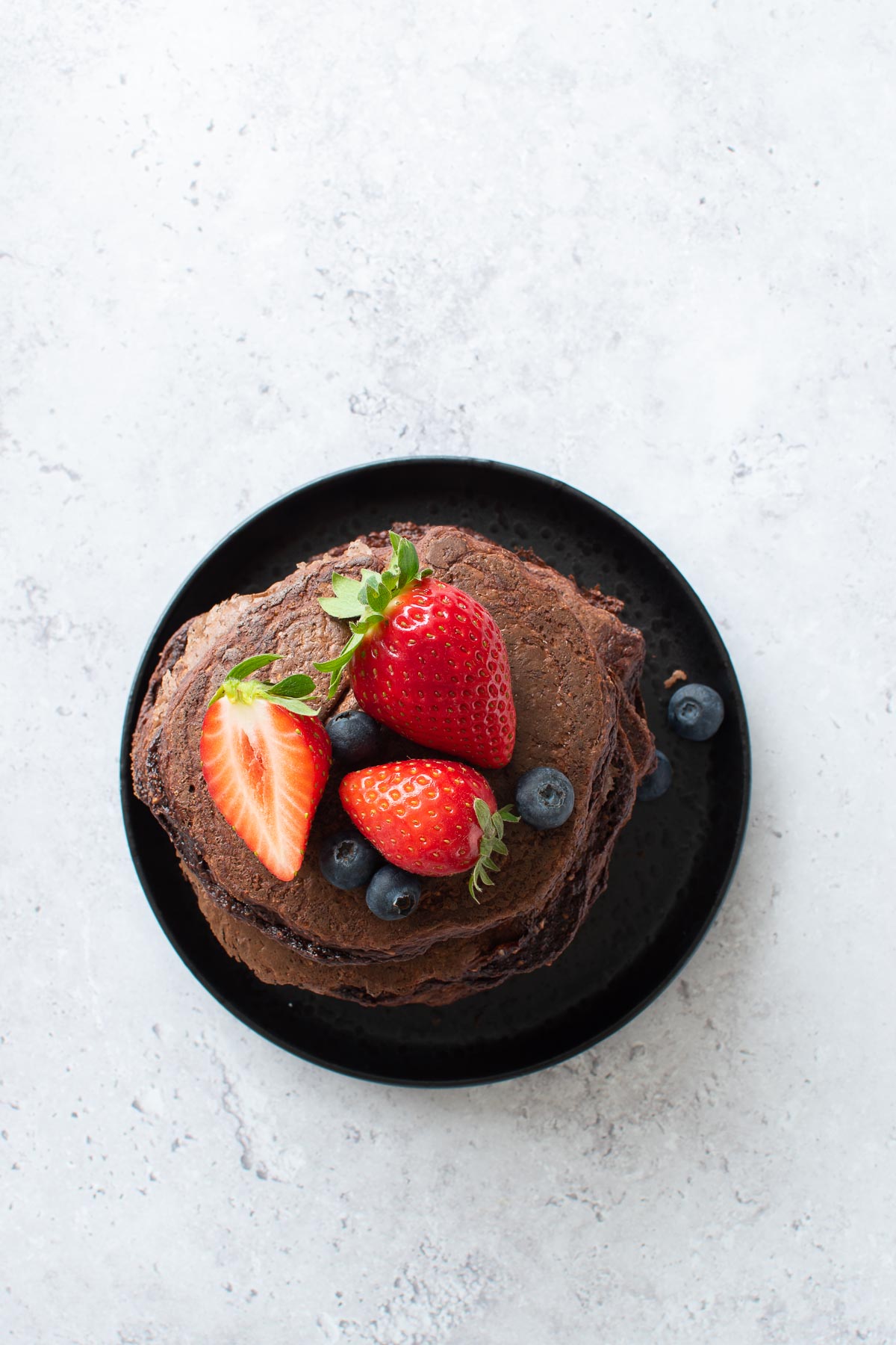 A plate with chocolate pancakes with protein powder.