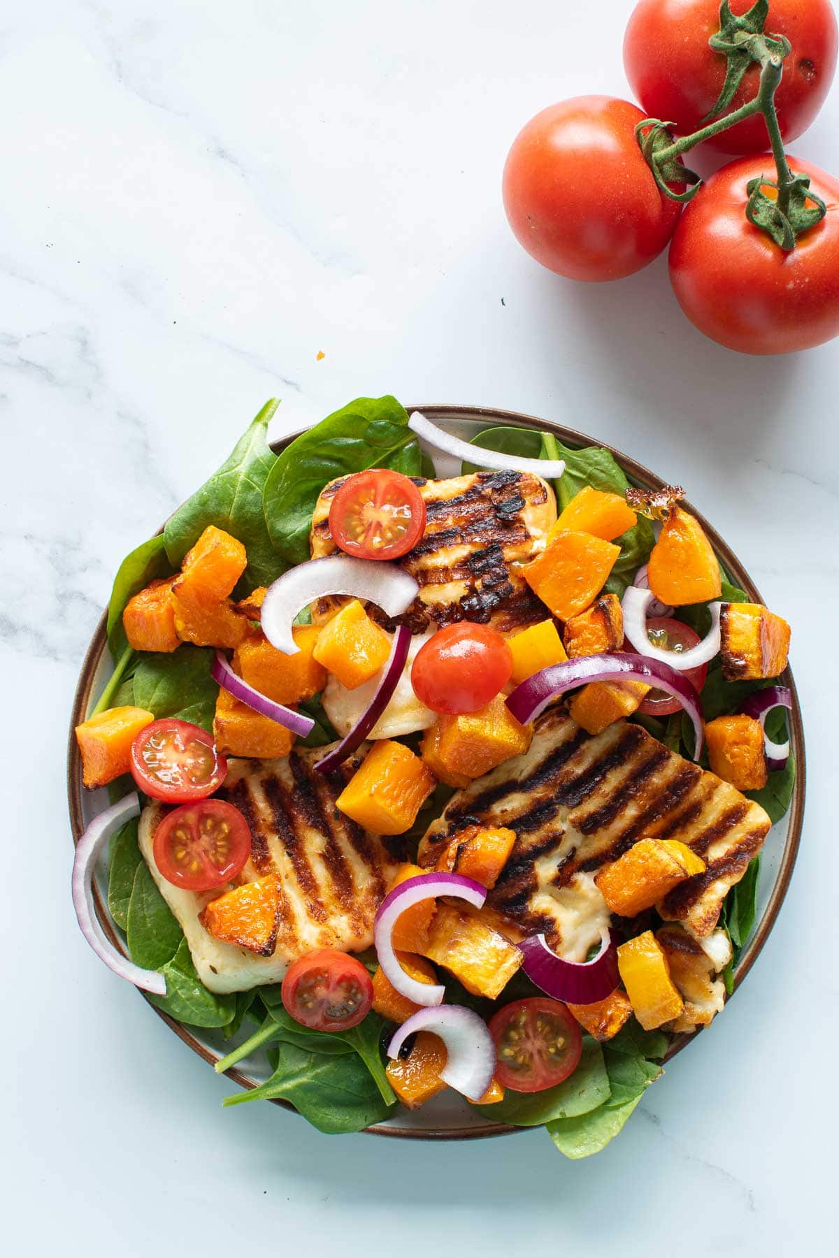 Close up of a plate with halloumi and squash salad.