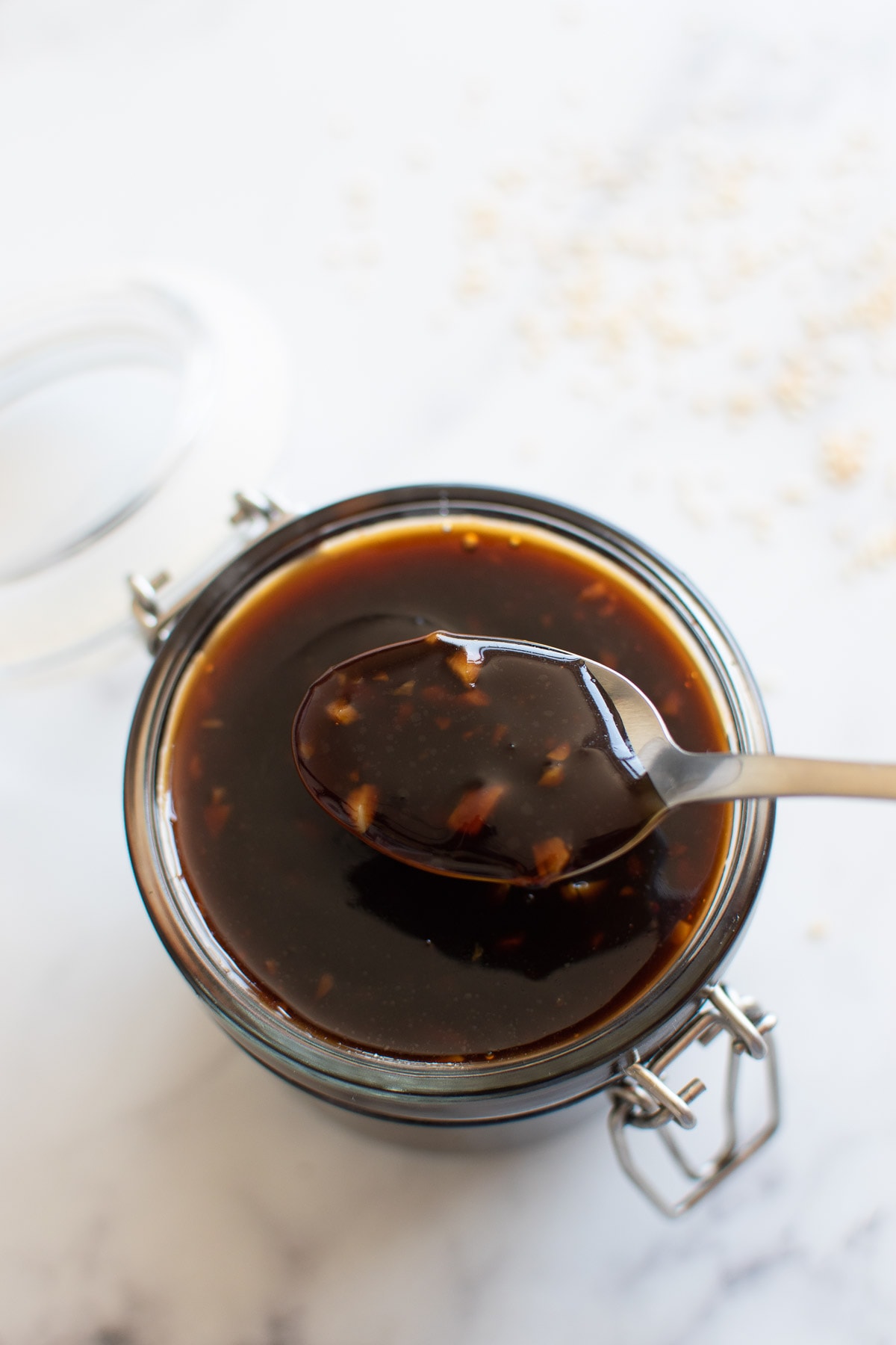 A jar of teriyaki sauce, with a spoon lifting up a serving.