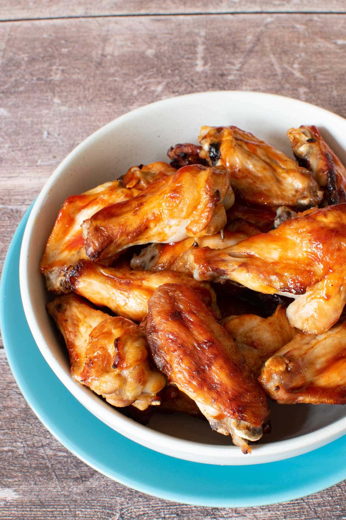 A bowl of chicken wings with sriracha and honey.