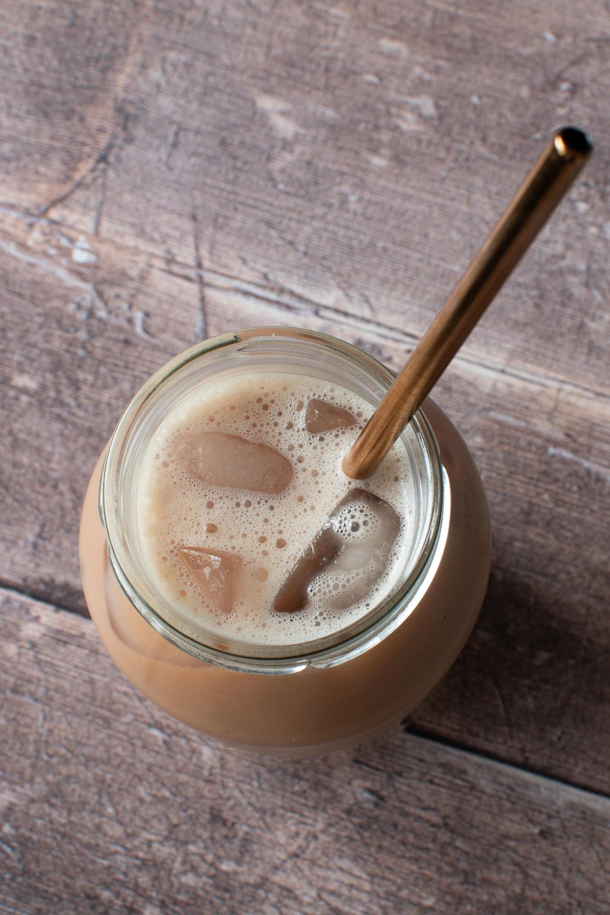 Iced chai latte in a glass with a metal straw.