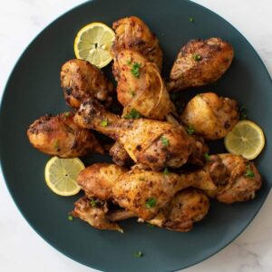 Instant pot drumsticks on a plate with lemon slices.